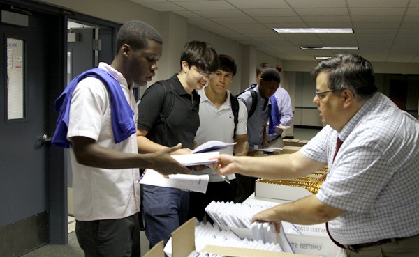 Senior Efosa Eboigbe receives his student planner from Mr. Mahne in the line just outside the Student Commons on Tuesday, August 1. Seniors, juniors, and sophomores attended the first of two Book Days that kicked off the 2013 - 2014 school year.