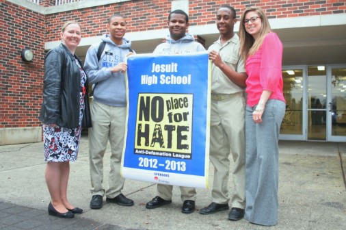 During morning assembly, coordinator of diversity Lori Fasone and seniors Mark Woods, Herbert Spurlock, and Chris Sylvain accept a "No Place for Hate" banner from a representative of the Anti-Defamation League.