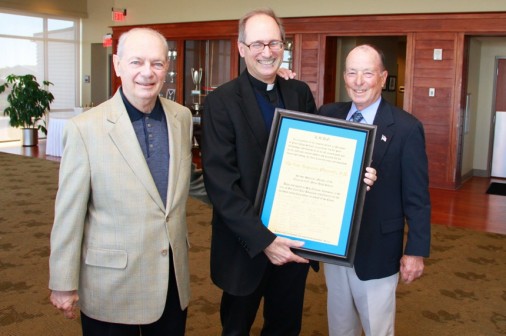 Russell "Pat" White and Charles "Skip" Hanemann of the Class of 1956 present a proclamation to Fr. Raymond Fitzgerald making him an honorary member of the Class of '56.