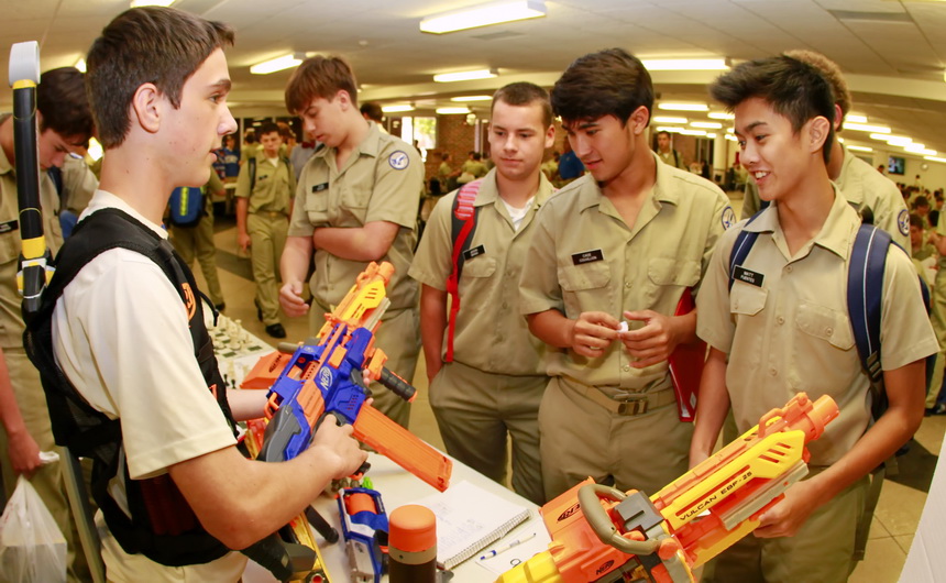 Junior Noah Billeaud-LeHotsky explains a Nerf Blaster's capability of projecting foam darts across the Student Commons to a trio interested in  the co-curricular group which holds Nerf wars, a great way to relieve tension. (Go figure.) Keeping an open mind about Nerfing are sophomore Jason Grana and juniors Cade Couvillion and Matt Fuentes. The second and final day of Rush 2014 takes place Thursday, September 11, in the Commons.