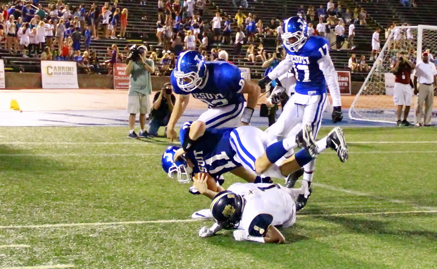 Jesuit quarterback Trey LaForge (11) dives into the end zone to score the Jays' fifth touchdown of the first half against Holy Cross in Friday night's Great American Rivalry game. Tight end Foster Moreau leaps over LaForge while wide receiver Kalija Lipscomb (17) tries to shake off a Tiger defender who the ref thought was holding, hence the flag coming in at left.