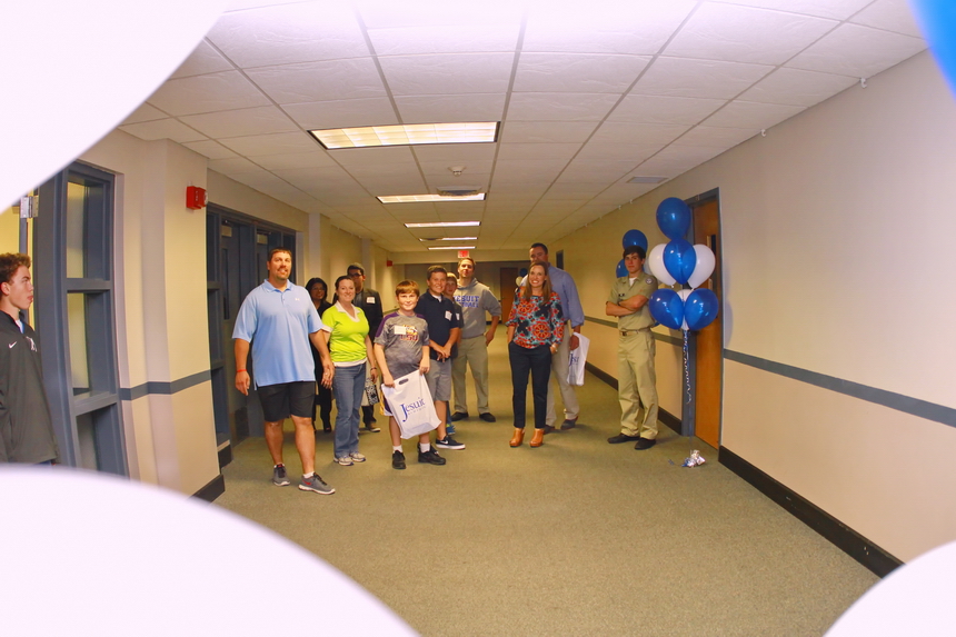 Seniors Billy McMahon (center, in sweatshirt) and Garret Perez (right) escort their guests from the Student Commons and down the first floor hallway.
