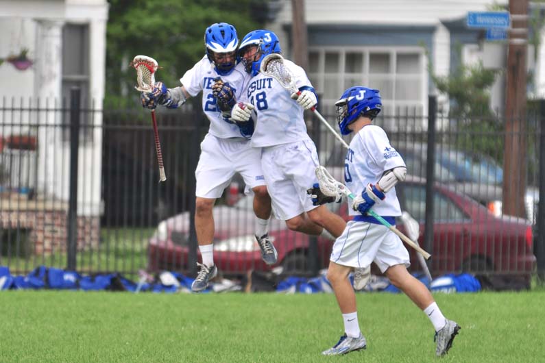 Flying Jays: seniors Billy McMahon (22) and Garrett Perez (28) go airborne to celebrate Perez puts the Jays on the scoreboard. Jesuit defeated St. Paul's, 7-2, on Saturday, March 21, on Jesuit's Will Clark Field.