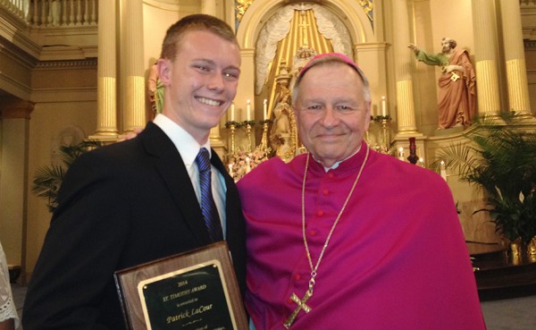 Archbishop Gregory Aymond presents senior Patrick LaCour with a plaque recognizing him as at St. Timothy Award recipient, one of just 17 youth in the archdiocese recognized with the prestigious award.