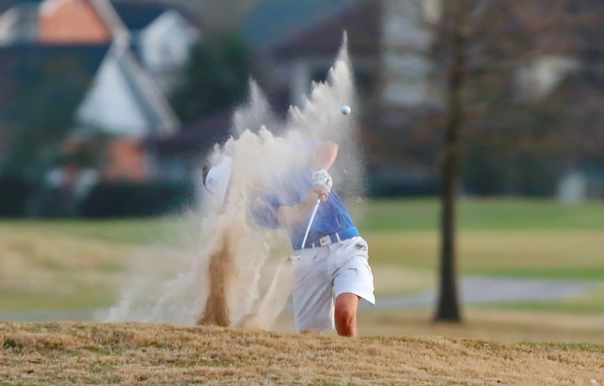 Sophomore Grayson Glorioso blasts out of a fairway bunker on the par four second hole.