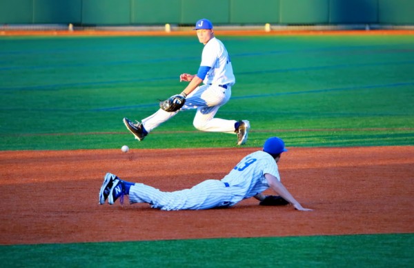 Third baseman Hunt Conroy dives for a sharply hit grounder that gets past him. However, shortstop Nick Ray hustles over and snags the ball, throwing to first base in time to get the out.