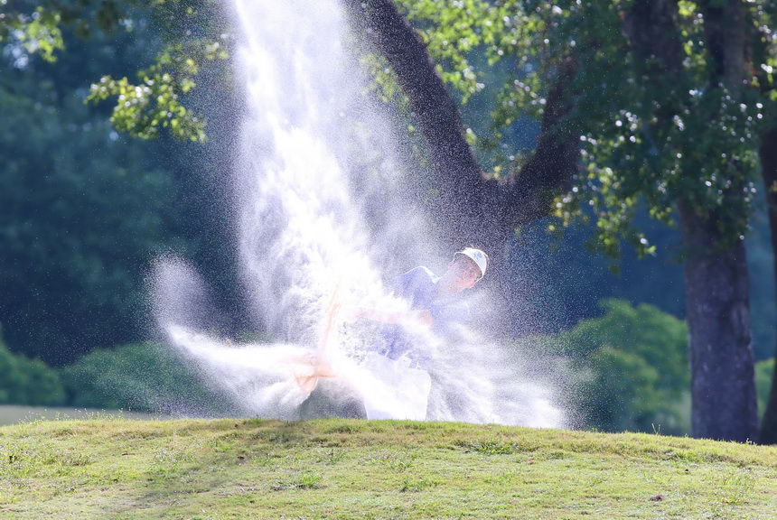 Nolan Lambert blasts out of a fairway bunker on the first hole.