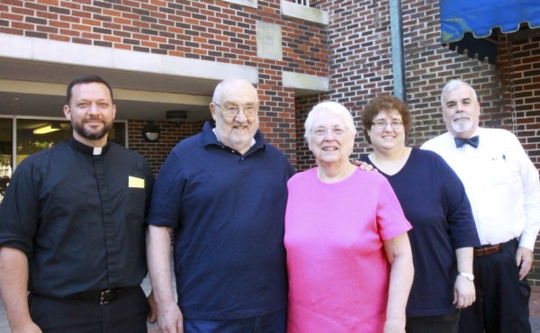 Fr. John Brown, S.J., (right) and Tim Powers (left) meet with the Frank, Connie, and Audrey Kielbasa underneath the stone medallion dedicated to their relative, Fr. Walter Ciszek, S.J.