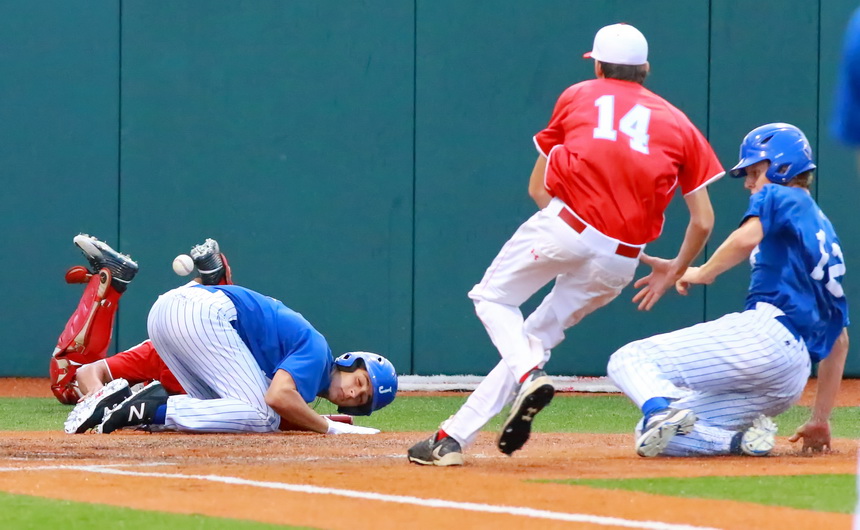 On a wild pitch, Grant Saunders (12) comes sliding home as Bryce Musso, who was at bat, ducks to avoid interfering with the play at home. Saunders was safe.