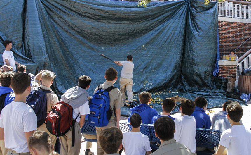 Students look on as a batter smashes a piece of rotted fruit during Friday's Homecoming Week lunchtime activity.