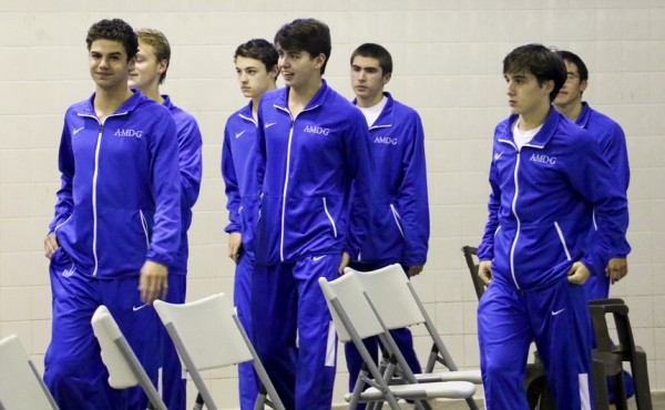 Senior swimmers walk around the pool to receive their first place district trophy.