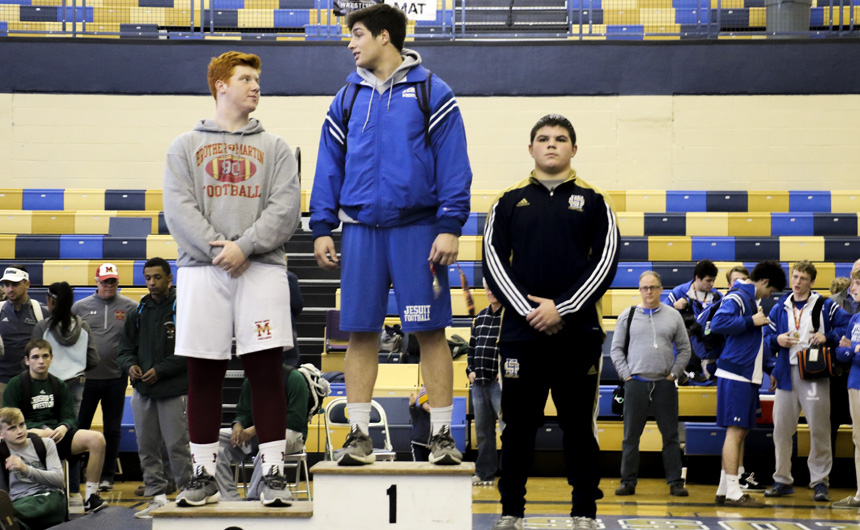 Junior Perry Ganci (220) stands on the high step of the awards podium. Ganci finished as the district champion of his weight class.