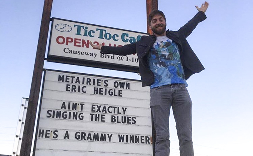 Jesuit's own Eric Heigle '02 stands in front of the Tic Toc Cafe's congratulatory sign.